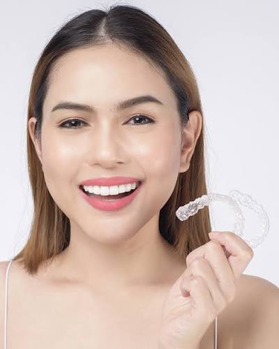 Woman holding a clear Invisalign aligner